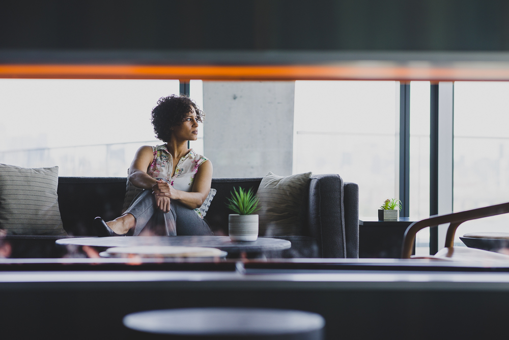 Afro-Latina girl sitting on couch looking to the left with a fireplace in a condo