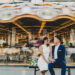 A bride and groom sitting on a bench in front of Jane's carousel in Brooklyn