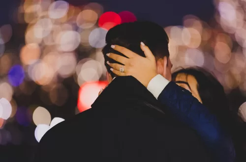 Engagement ring holding the neck of someone with bokeh of night lights