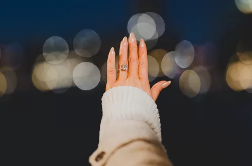 Woman's hand with an engagement ring and bokeh lights in the background