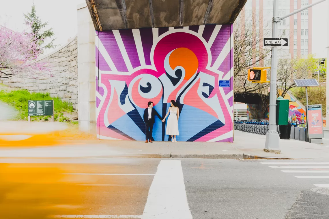 Asian couple in front of graffiti love sign with a yellow blur passing through