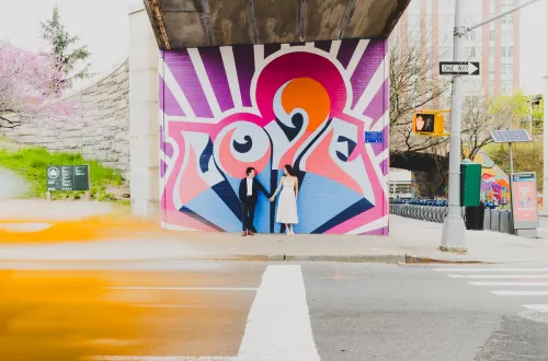 Asian couple in front of graffiti love sign with a yellow blur passing through