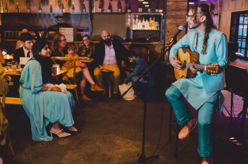 Couple celebrating Sangeet with a performance: one of the couple on guitar and the other listening.